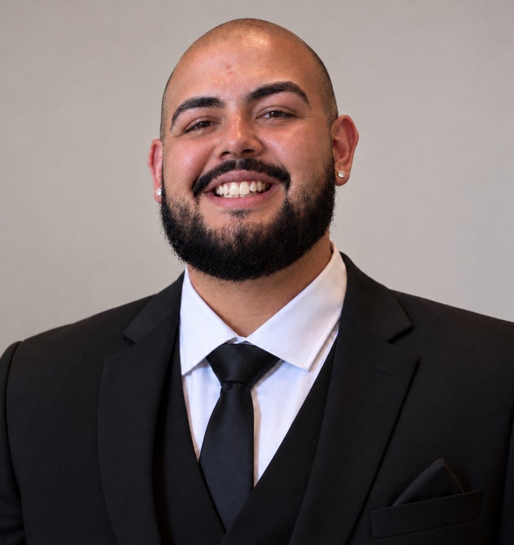 Izaak Varela, licensed life insurance agent, smiling in a dark suit and tie